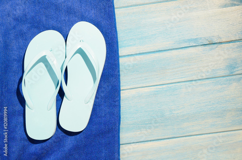 flip flops and towel on blue wooden table with sunlight