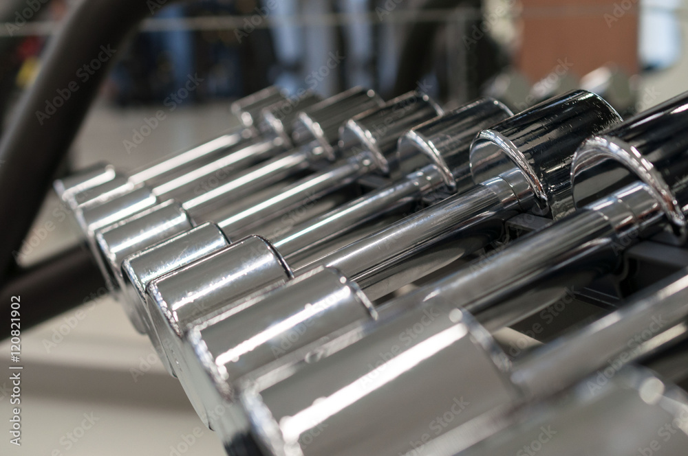 Metal dumbbells lying in a row at the gym Metal dumbbells lying in a row at the gym