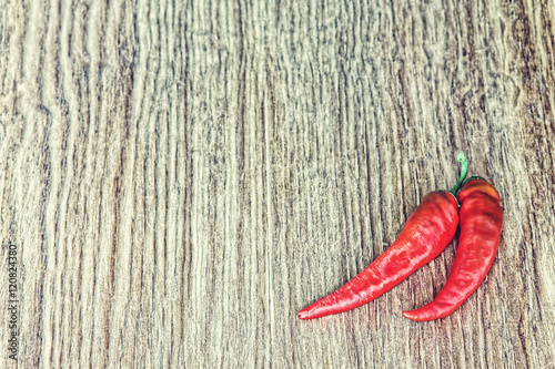 Two Red Hot Chili peppers on grunge wooden background.Toned image.