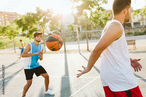 Portrait of two friends playing basketball on court.