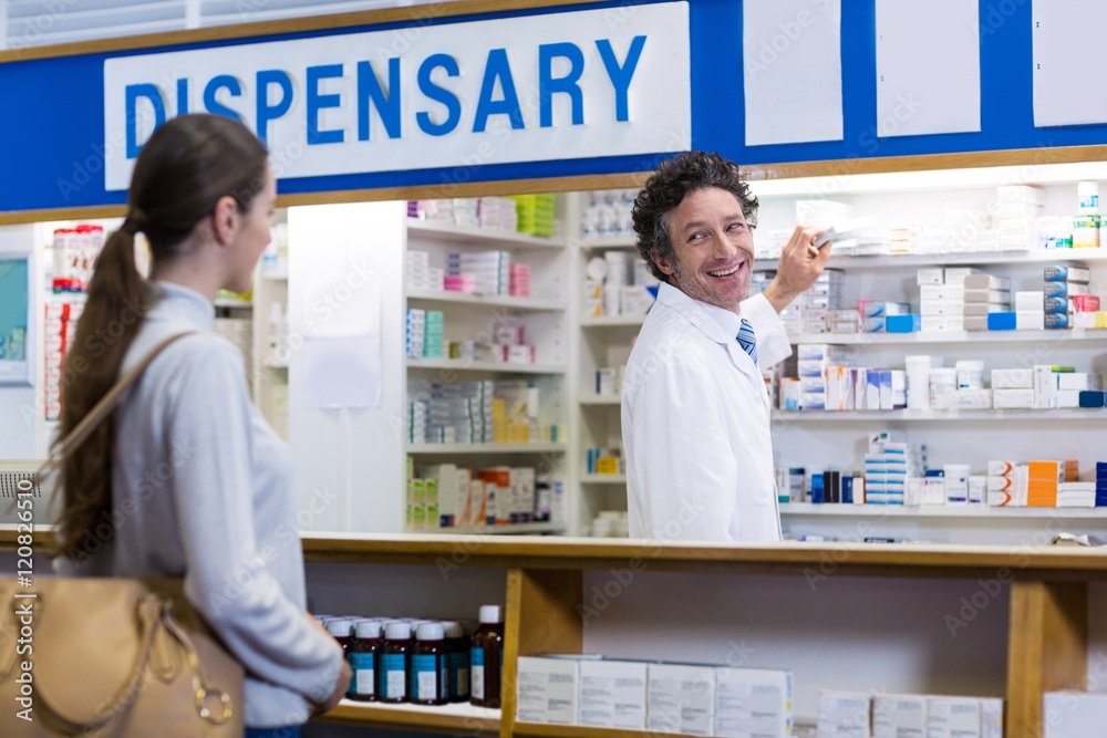 Pharmacist showing the medicine box to customer Pharmacist showing the medicine box to customer
