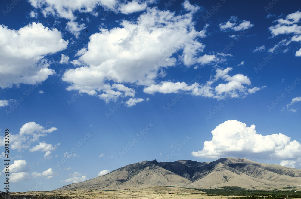 Mount Aragats in the autumn sunny day against the blue sky covered by clouds
