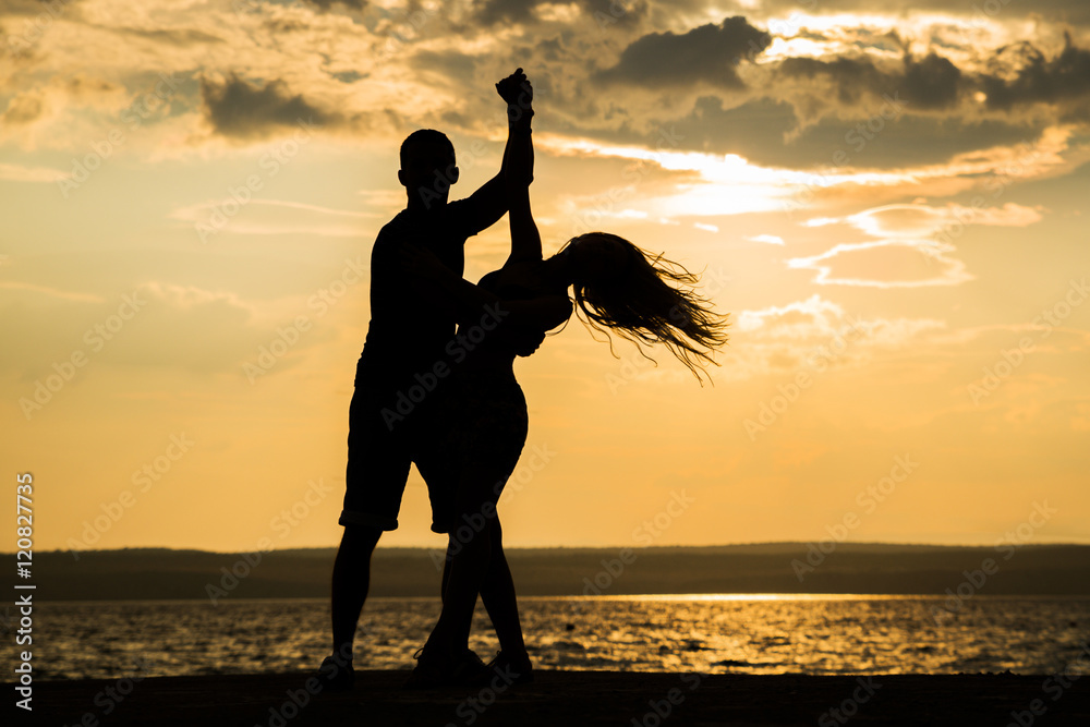 Couple dancing at sunset salsa / brazilian zouk. Lovers, dance partners spinning, latin festival dance concept.