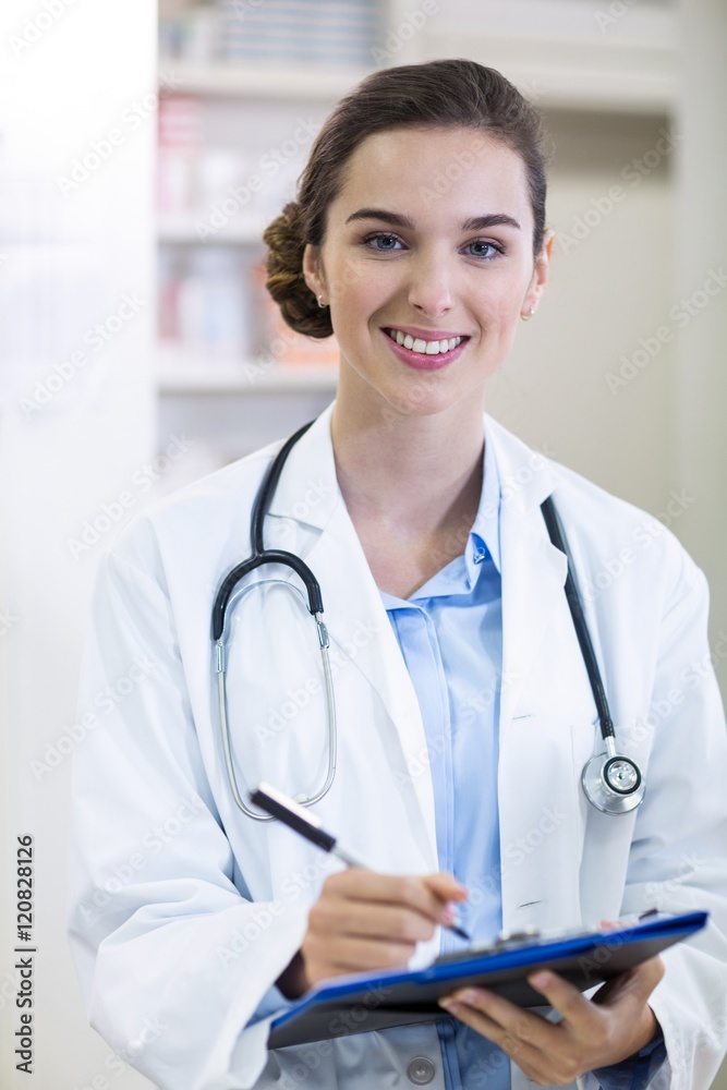 Pharmacist writing on clipboard in pharmacy Pharmacist writing on clipboard in pharmacy