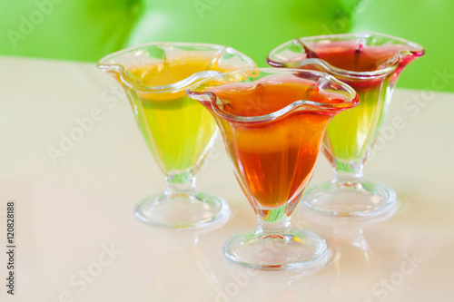 Red yellow jelly in glass plate, citrus fruit gelatin dessert beige background. soft focus