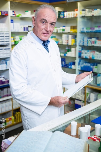 Pharmacist holding a clipboard in pharmacy