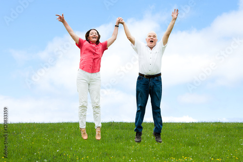 Senior Couple Jumping On Field