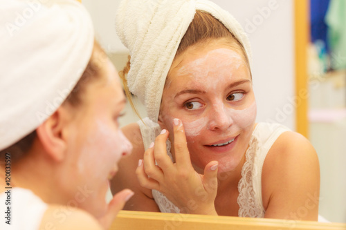 Woman applying mask cream on face in bathroom