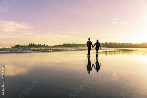 Sunset at the beach. Tofino Long Beach during the summer. Couple going for a walk as the sun sets.  photo