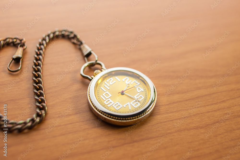 Pocket watch on wooden, close up, some blurred area.