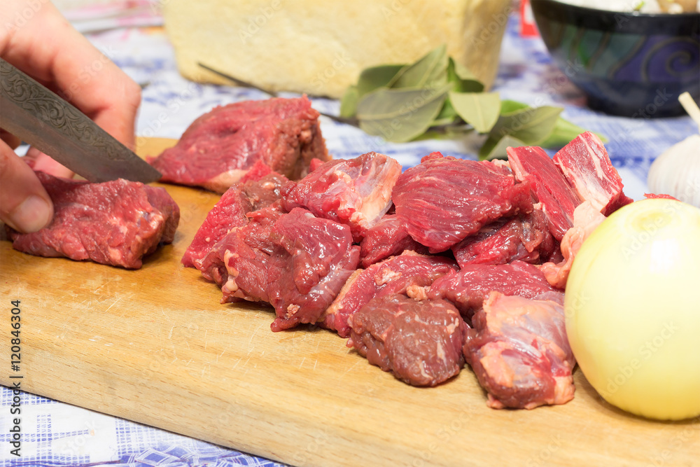 man chef cuts pieces of beef. selective focus