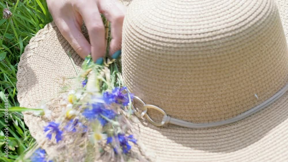 View of female hands putting flowers on the straw hat, steadycam shot
View of female hands putting flowers on the straw hat, steadycam shot