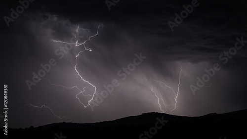 Lightning strike over mountain range with clouds
