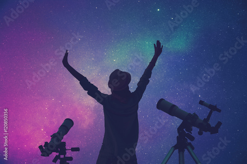 Girl enjoying starry skies with telescopes beside her.