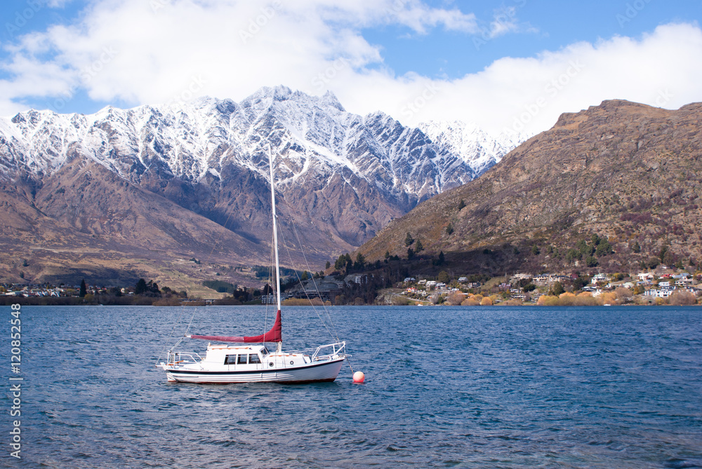 White boat in a lake with snow covered mountains, New Zealand