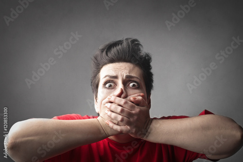 Scared woman covering her mouth with her hands photo