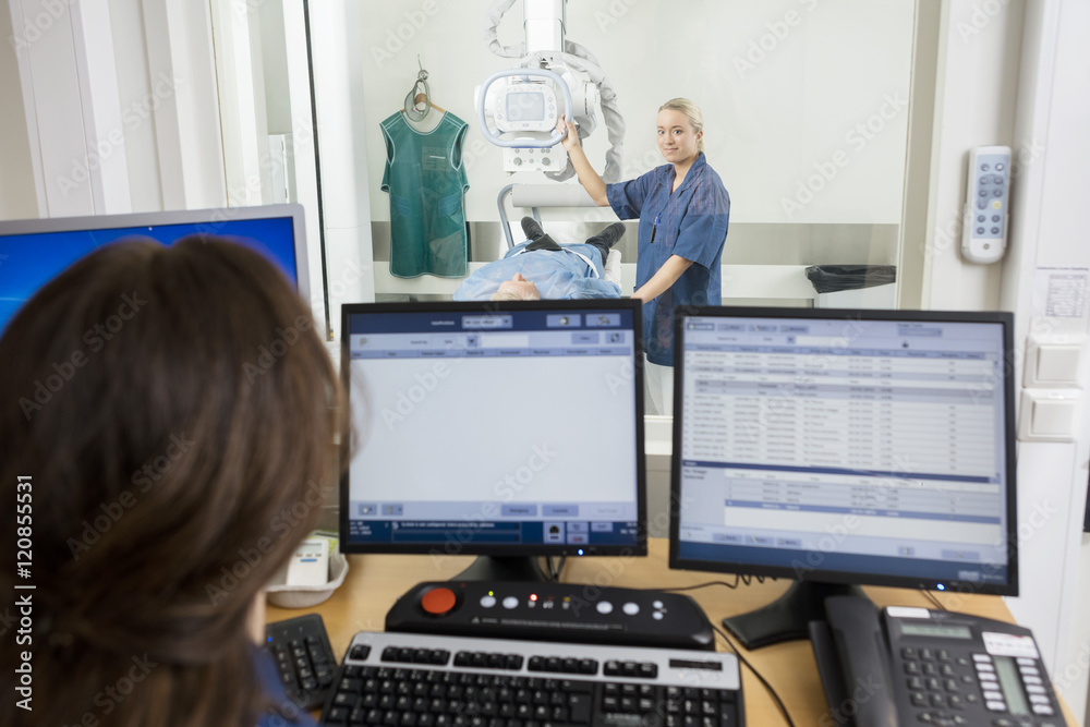Radiologist Taking Patient's Xray While Coworker Using Computers Radiologist Taking Patient's Xray While Coworker Using Computers