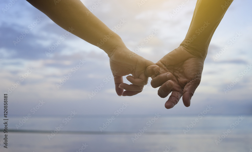 close up hand of senior couple hook each other's little finger together near seaside at the beach,filtered image,selective focus,light effect added,love forever concept close up hand of senior couple hook each other's little finger together near seaside at the beach,filtered image,selective focus,light effect added,love forever concept