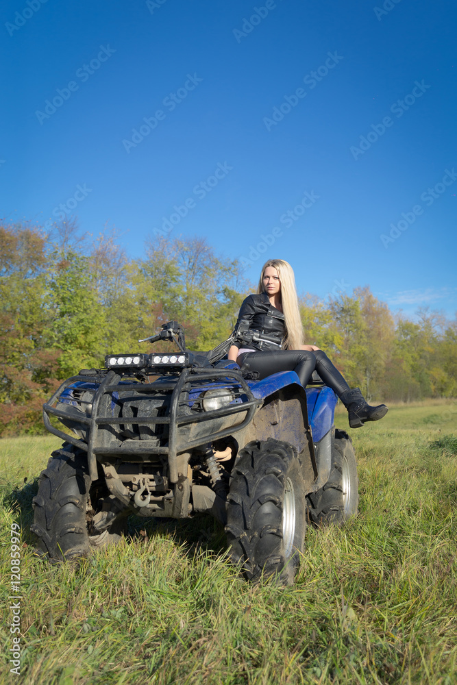Fototapeta premium Elegant blonde woman riding extreme quadrocycle ATV on summer fi