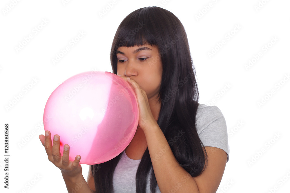 Attraktive, farbige Frau pustet roten Ballon auf Attraktive, farbige Frau pustet roten Ballon auf