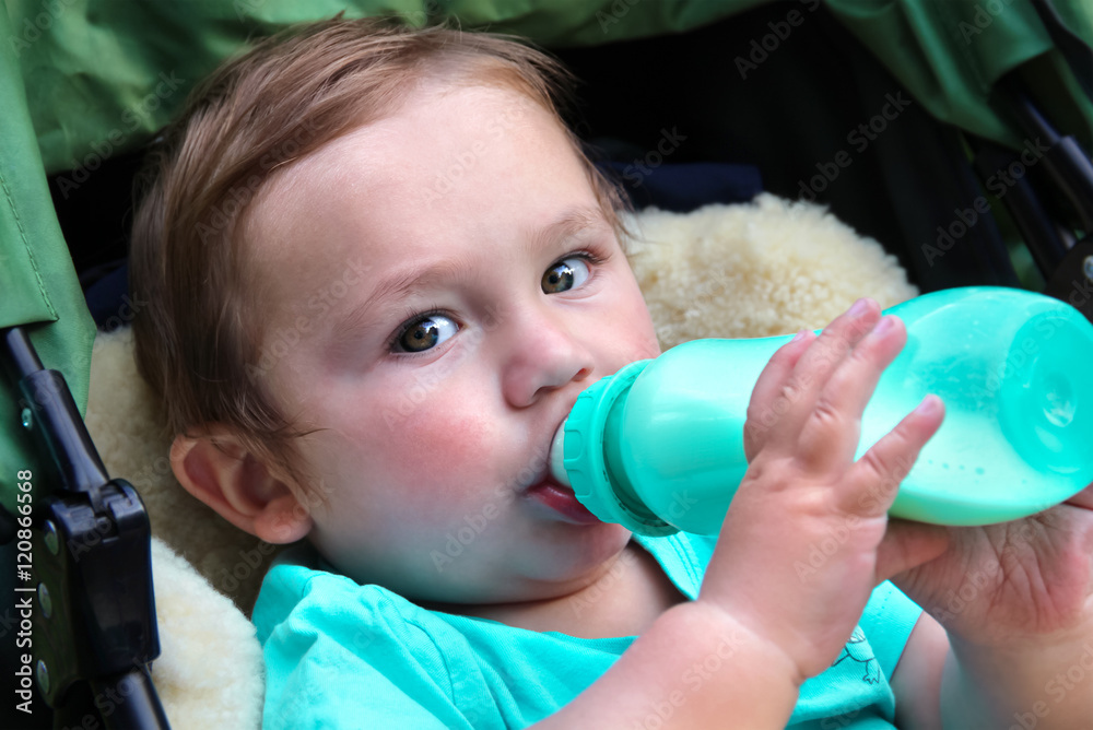 Baby hält und nuckelt an Babyflasche StockFoto Adobe Stock