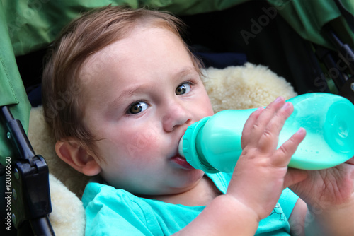 Baby hält und nuckelt an Babyflasche photo