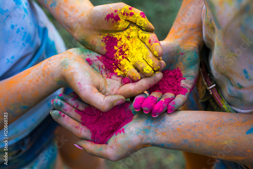 Yellow and crimson holi paint in girls hands