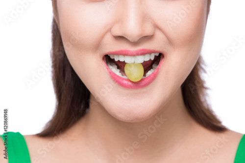 Young beautiful asian woman eating fresh grapes isolated on whit