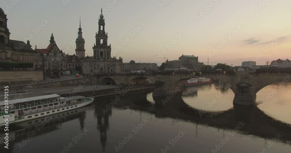 Aerial camera rises over the Elbe River with Katholische Hofkirche and the Augustusbruke in shot.The sun is setting in the background Aerial camera rises over the Elbe River with Katholische Hofkirche and the Augustusbruke in shot.The sun is setting in the background