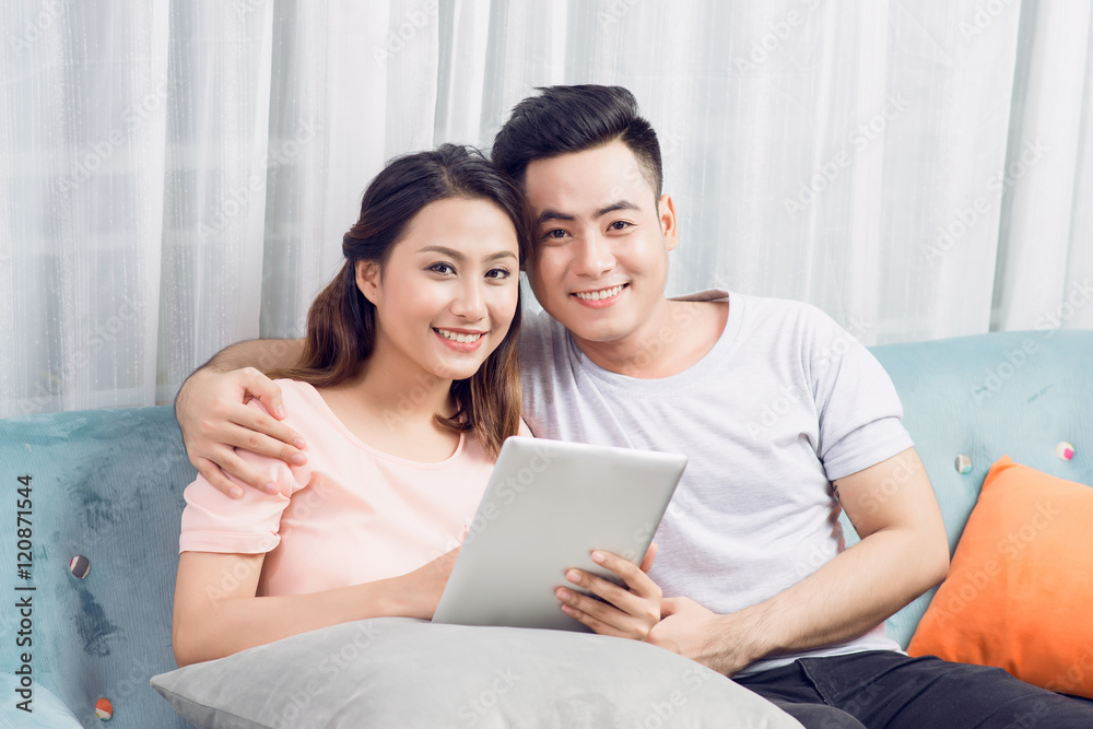 Couple at home relaxing on sofa with digital tablet Couple at home relaxing on sofa with digital tablet