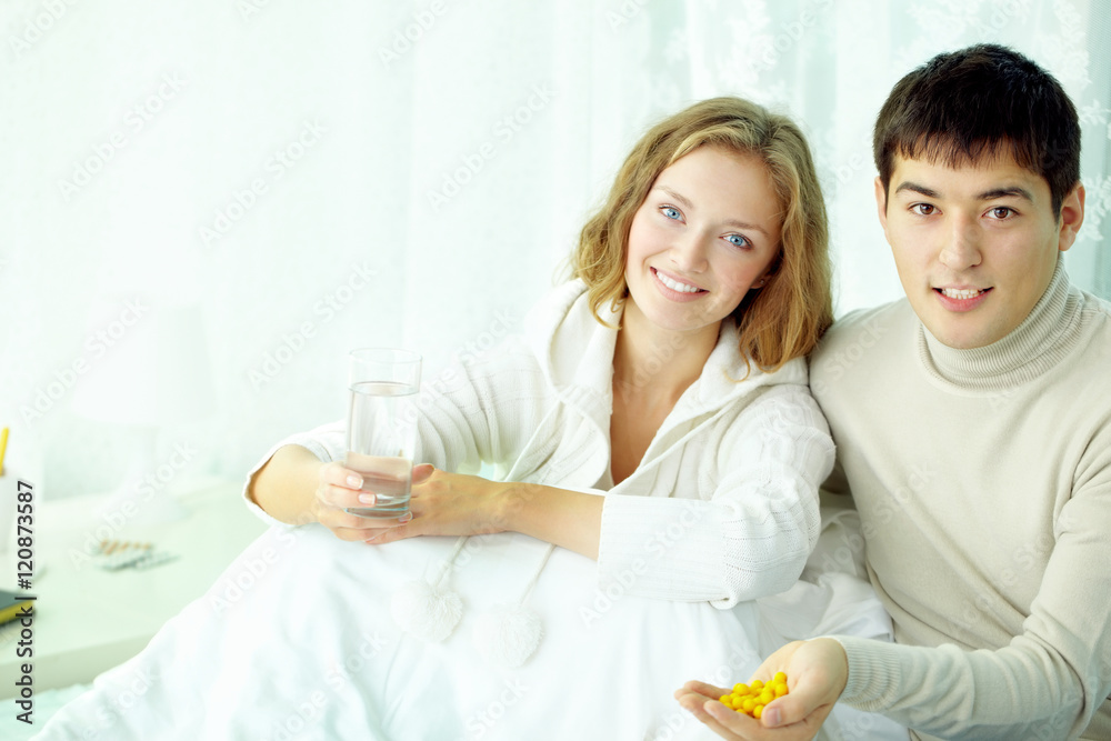 Portrait of young married couple with vitamin pills looking at camera and smiling Portrait of young married couple with vitamin pills looking at camera and smiling