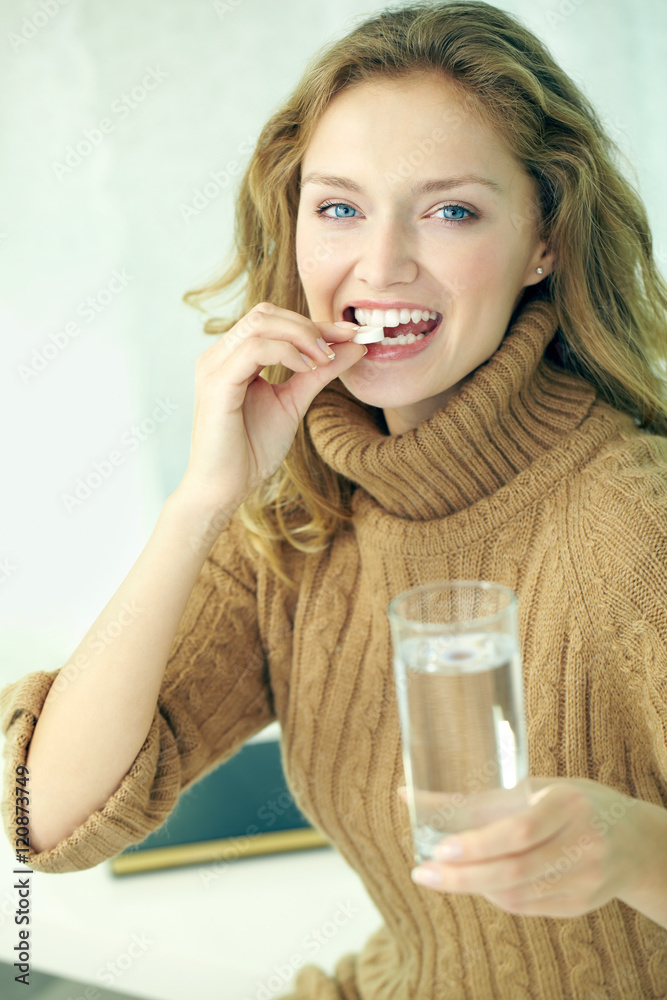 Portrait of young healthy woman taking a pill