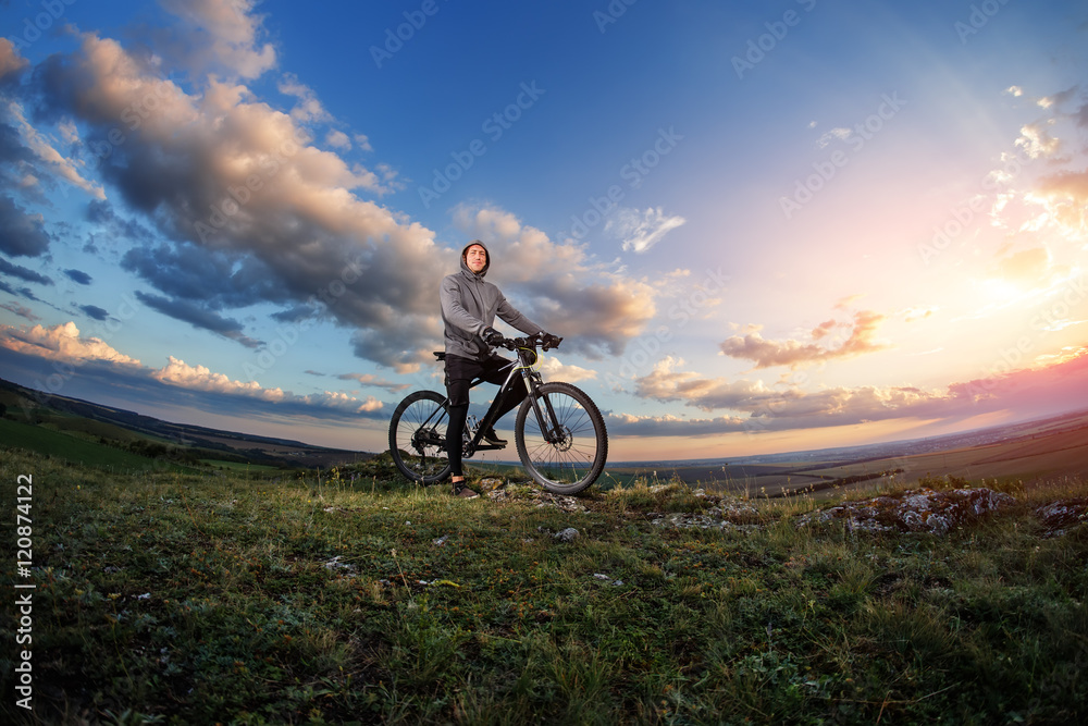 Young man cycling on a rural road through meadow