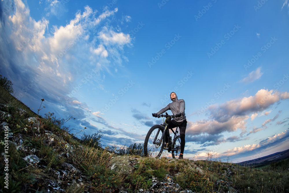 Fototapeta premium Young man cycling on a rural road through meadow