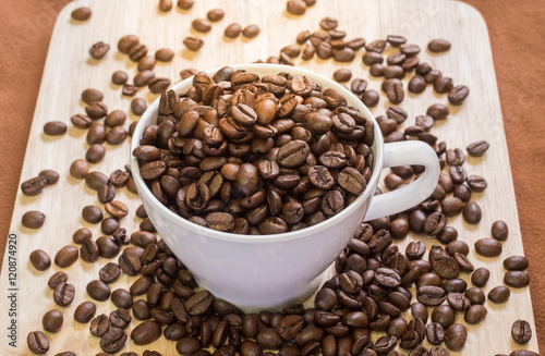 Coffee Cup with coffee beans on wood of coffee beans background.