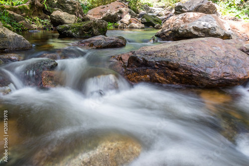 Waterfall cascades flowing over flat rocks in forest.