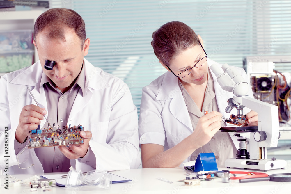 Two young engineers working with transistor in lab