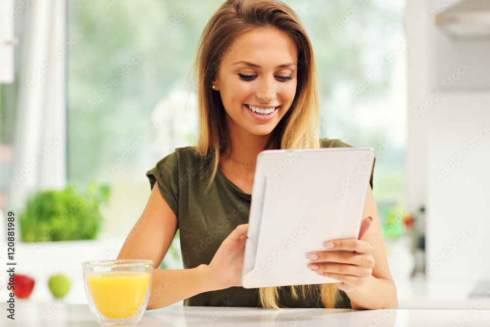 Young woman with orange juice and tablet in kitchen Young woman with orange juice and tablet in kitchen