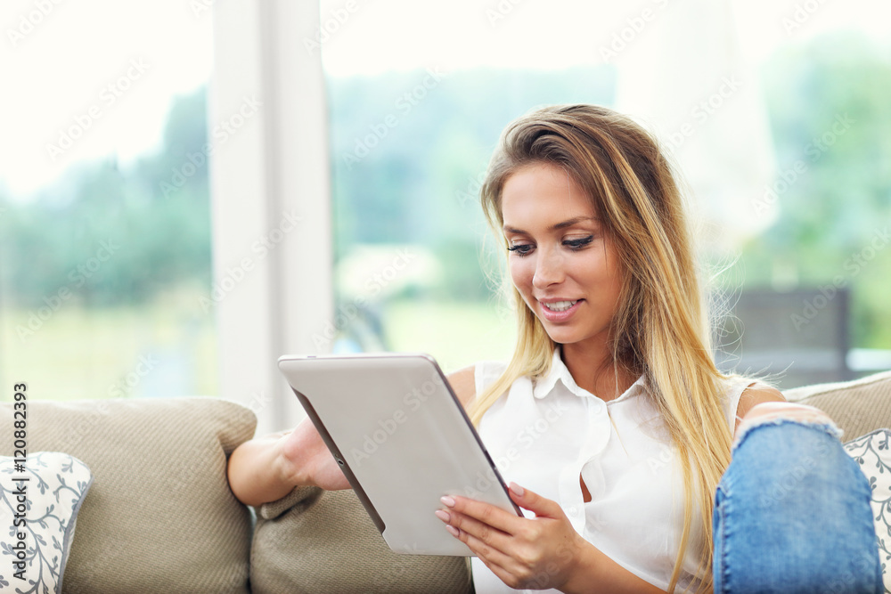 Woman on couch with tablet in living room Woman on couch with tablet in living room