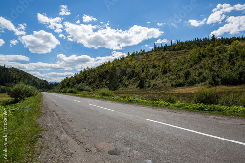 Empty road and mountains on background of the cloudy sky