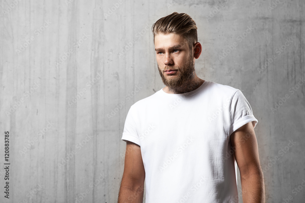 Portrait of bearded man in white t-shirt standing on the cement wall background Portrait of bearded man in white t-shirt standing on the cement wall background