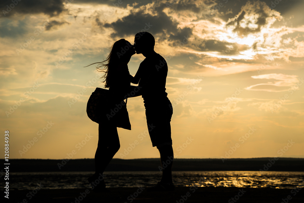 Couple in love silhouette shadow, holding, kissing - seaside, ocean, water, sunset, sunrise background. Dating, romantic, vacation, valentine's concept.