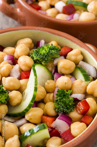 Chickpea salad in brown bowl on wooden background    