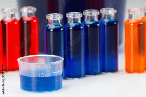 Blue, red and orange liquid in chemical lab test tubes on white background