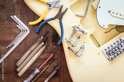 yellow electric guitar on wood in repair & luthier workshop, fixing & musical instrument repairing concept