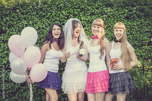 Beautiful bride and happy bridesmaids celebrating hen-party.Happy young hipster girls having fun at bridal shower, wearing colorful fluffy skirts and white t-shirt outdoors in city park on a sunny day