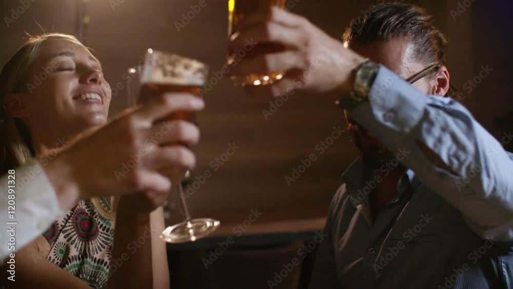 Cheerful group of three young friends enjoy a glass of wine and beer and toasting at elegant bar on glamour party Cheerful group of three young friends enjoy a glass of wine and beer and toasting at elegant bar on glamour party