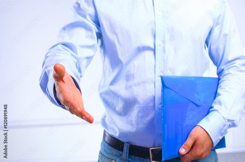 businessman with papers holds out his hand for a handshake businessman with papers holds out his hand for a handshake