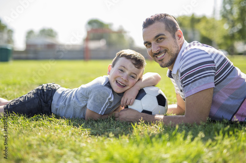 man with child playing football on field