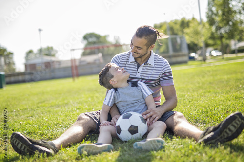man with child playing football on field